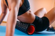 Eine Sportlerin massiert ihren Rücken mit einer Faszienrolle Eine Sportlerin massiert ihren Rücken mit einer Faszienrolle